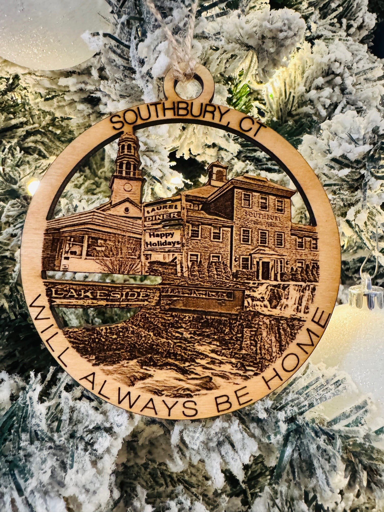 Decorative Christmas ornament with a town scene and text on a tree.
